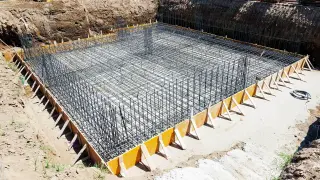 Siatka prętów tworzy zbrojenie płyty fundamentowej, gotowe do zalania betonem. Solidna podstawa przyszłego budynku.